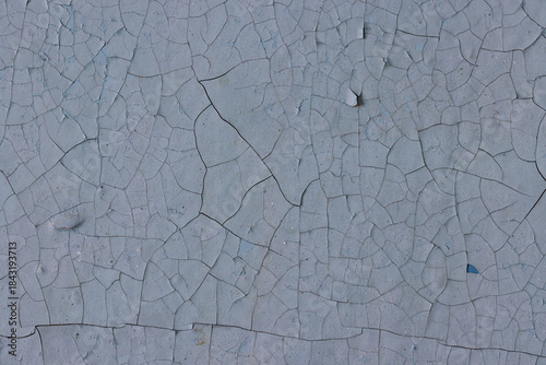 Peeling paint on the wall. Old concrete wall with cracked flaking paint. Weathered rough painted surface with patterns of cracks and peeling. Grunge texture for background and design. High resolution.