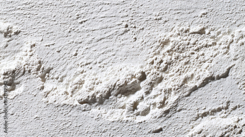 Close-up texture of rough white plaster with shadows and highlights. Detailed view of a textured white surface showing unevenness and granular details with dramatic lighting.