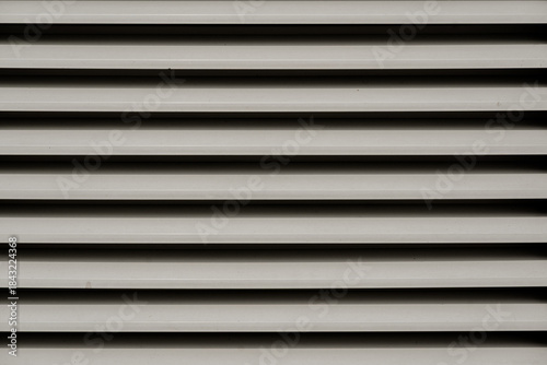 Bilde på lerret Abstract close-up of horizontal metal ventilation louvers creating a linear shadow pattern
