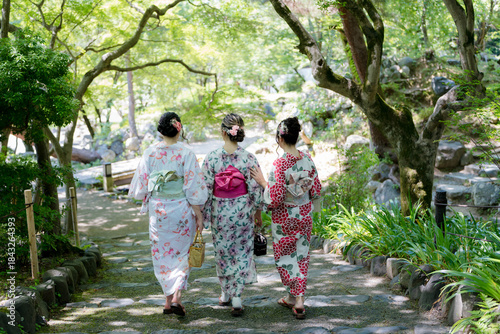 фотографія Female friends in yukata walking down stone steps in fresh green garden