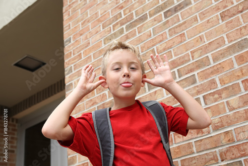 Boy acting silly making a funny face outside of a school