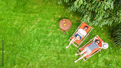 Photos Young girls relax in summer garden in sunbed deckchairs on grass, women friends