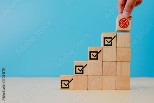 Corporate regulatory and compliance. Goals achievement and business success. Project and goals tracking. Task completion. Managing project timeline. Holding wooden cube with target achievement icon.