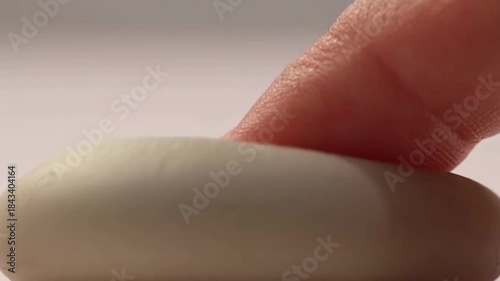 Finger pressing soft clay surface showing elasticity and impression closeup