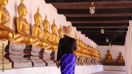Female Admiring Rows of Gorgeous Seated Buddha Images at the Cloister of Wat Phutthaisawan Historic Buddhist Temple in Ayutthaya, Thailand