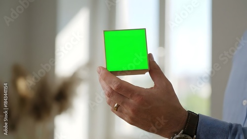 Person Holding Green Cube in Hand Indoor.