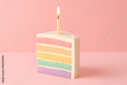 A vibrant slice of layered birthday cake with pastel colors, a lit candle on top, set against a soft pink background with a white foreground