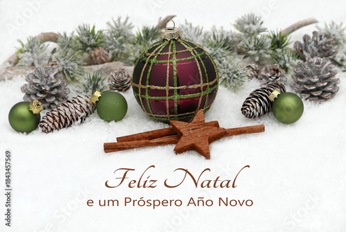 Cartão de Natal: Saudações natalinas em português com enfeites de Natal e ramos de pinheiro na neve. Feliz Natal e um próspero Ano Novo.