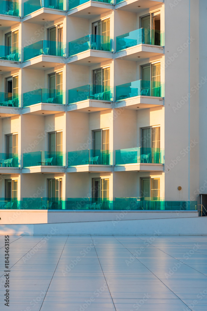 Fototapeta premium Sunlit turquoise glass balcony facades of a modern hotel resort with repeating pattern