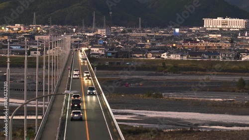 河川にかかる橋の上を車が走る夕方から夜の風景
