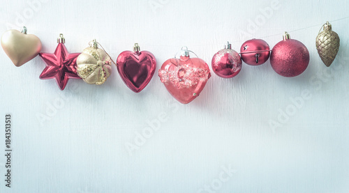 Red and golden christmas decorations hanging on a white background; copy space