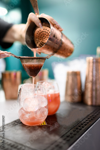 Bartender Pouring Amber Cocktail Over Ice