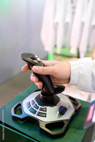 A close-up of a hand gripping a flight simulator joystick mounted on a control base with multiple buttons and a throttle lever