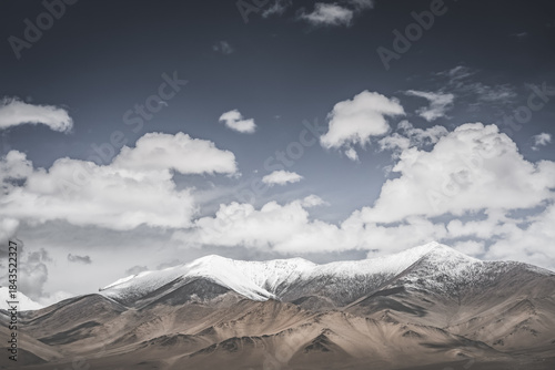 Landscape in the Pamir Mountains of Tajikistan with snow, glaciers, and cliffs, a panorama of mountains in cloudy weather for the background, nature in the Tien Shan highlands, landscape background