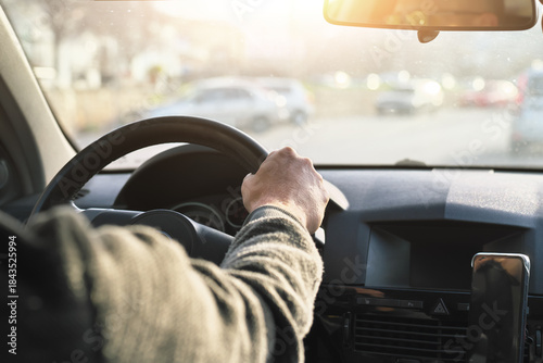 Men’s driver's hand holding steering wheel of car while driving.