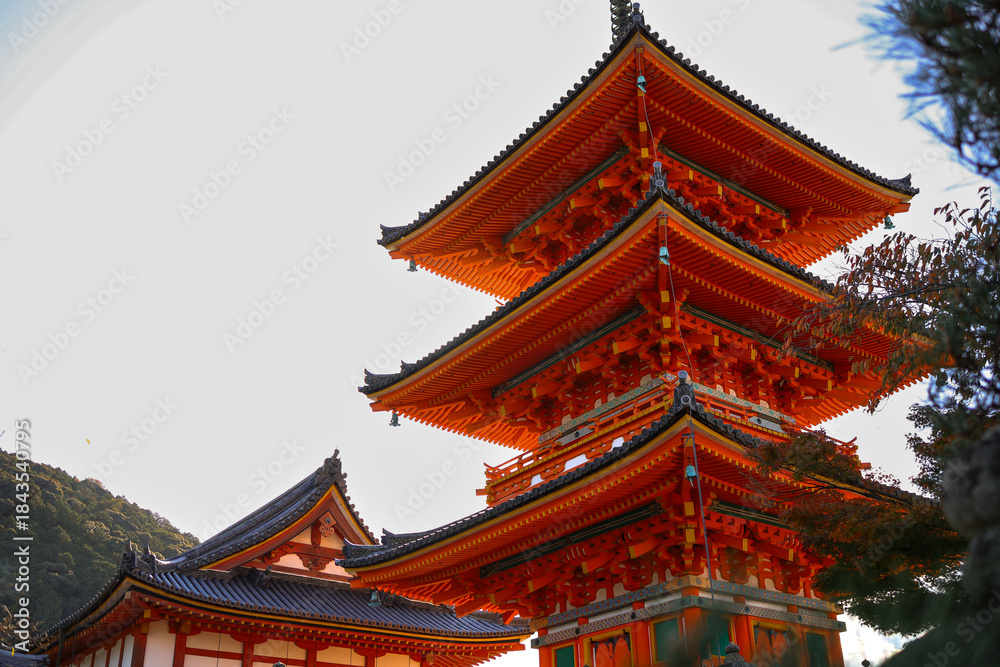 Fototapeta premium Kyoto. Bright Red Roof of a Japanese Temple with ornate wooden trim and stone steps under a clear sky