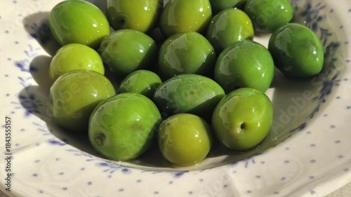 Fresh green olives spinning in a ceramic bowl