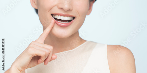 口元を指さす笑顔の女性