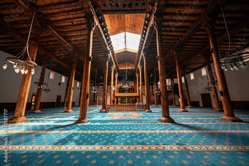 Foto Esrefoglu Mosque interior in Konya, Turkiye, showcasing carved wooden pillars, colorful tile motifs, rich patterns, and finely detailed Islamic craftsmanship