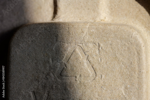 Fotografija Detailed macro shot of an industrial recycled paper or fiber egg carton, emphasizing the universal recycling logo and the textured, natural, and earthy brown surface