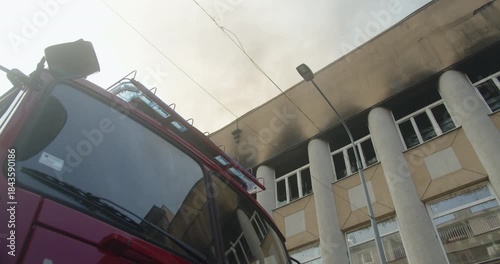 The flashing blue light of a truck fire, burning building in the background