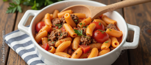 Delicious pasta dish with ground meat, tomatoes, and herbs served in white bowl, garnished with parsley, on wooden table