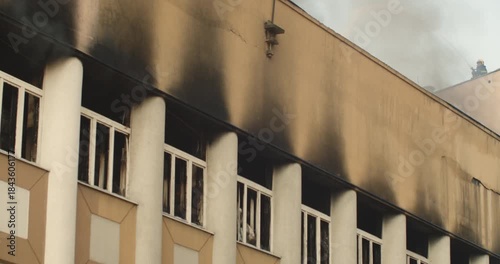 Firefighter extinguishing fire with a water gun on the roof of a burning building