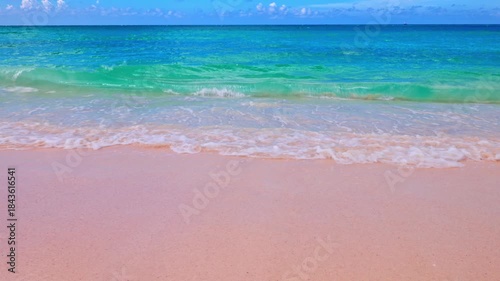 Beautiful view of gentle waves washing sandy Eagle beach of Caribbean Sea on background with blue sky. Aruba.