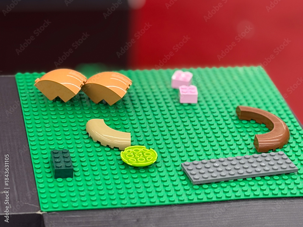 Fototapeta premium Colorful lego pieces on green baseplate