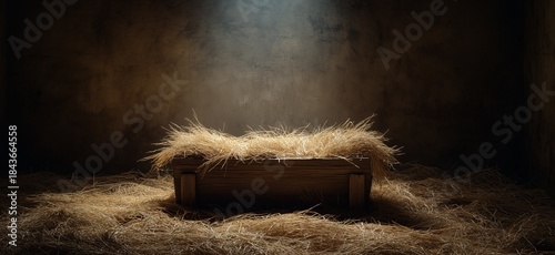 Wooden manger with straw under soft spot light. Empty wooden manger with straw receiving warm light, symbolizing birth and new beginnings