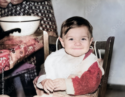 A vintage portrait of a smiling one-year-old girl wearing a bib while eating. Retro photograph from 1995.