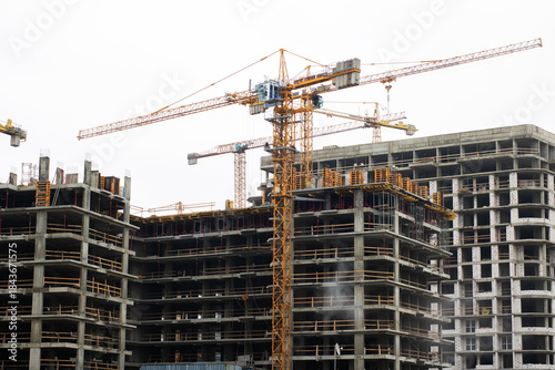 Construction rising under cloudy skies, Building site bustling with cranes and workers