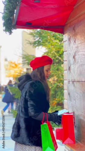 Elegant woman shopping at a festive Christmas fair with presents and paper bags