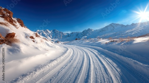 A captivating snowy road winds through majestic mountains under a bright sun, inspiring feelings of adventure and exploration in a winter wonderland filled with potential.