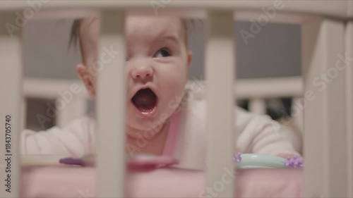 Adorable newborn baby yawning in a crib