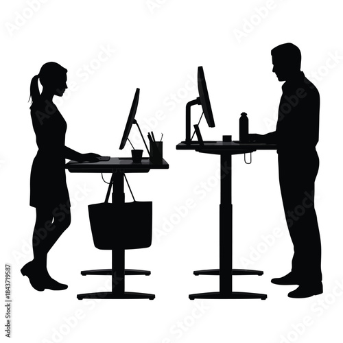 Silhouette of two people working at adjustable standing desks indoors
