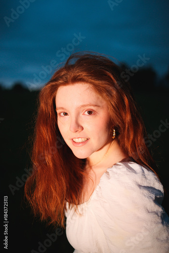 Young smiling redhead woman portrait at dusk
