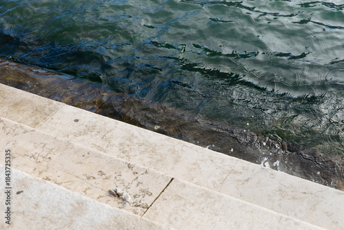 Fotografie Stone steps leading into rippling water at a lakeside