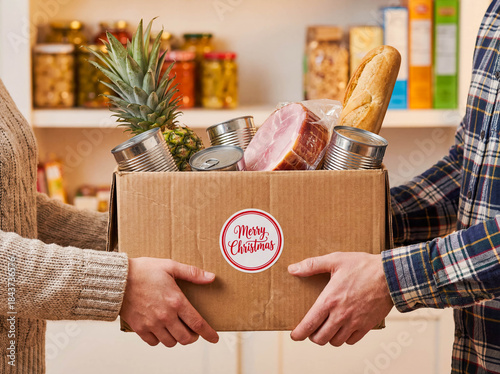 Hands passing box holiday groceries donation food drive christmas charity help poor family community harvest sharing volunteer kindness giving crate turkey canned goods festive season support concept