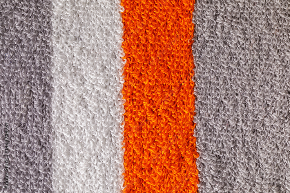 Fototapeta premium A close-up shot of a textured gray towel, with orange and white strips showcasing its fluffy and soft fabric loops. Horizontal photo