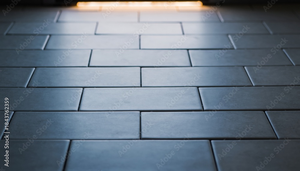 Fototapeta premium Close-up view of a textured surface composed of rectangular tiles with a subtle gradient of light illuminating from the top