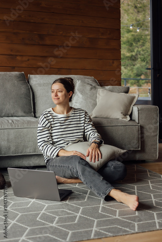 Woman working on a laptop while relaxing at cozy mountain cabin