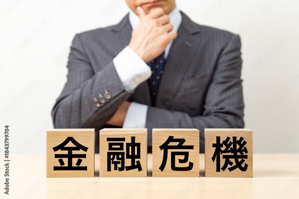 Obraz premium 「金融危機」と書かれたブロックとビジネスマン