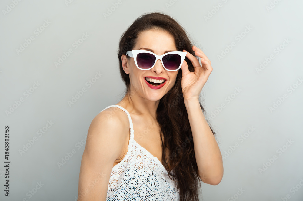 Naklejka premium Fun red lipstick happy toothy smiling fashion woman posing in fashion sunglasses and white top isolated on white wall background with empty copy space. Lifestyle casual portrait