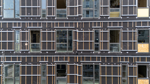 Façade de bâtiment en cours de travaux, illustrant un chantier de rénovation ou de construction avec des éléments structurels visibles et un environnement urbain en transformation.