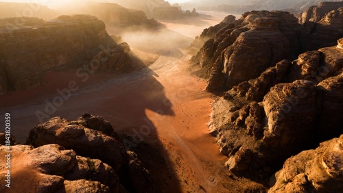 Golden hour aerial view of a dramatic desert canyon landscape with atmospheric mist