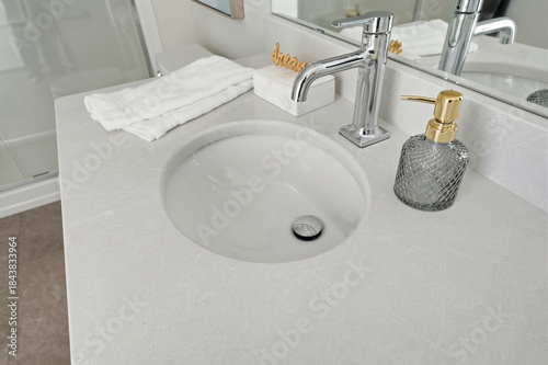 Bathroom sink with a soap dispenser and a towel on the counter