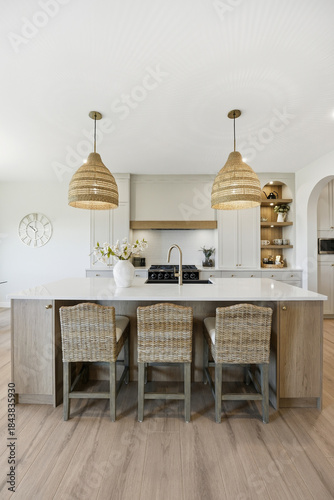 Kitchen with a white island and three wicker chairs