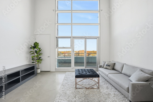 Large open living room with a white wall and a large window