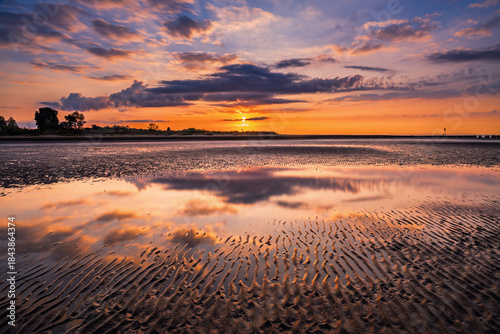 Fototapeta Naklejka Na Ścianę i Meble -  summer sunrise where the lagoon meets the sea with reflection of the clouds inside the puddles created by the tide, Bibione Pineda, Venice